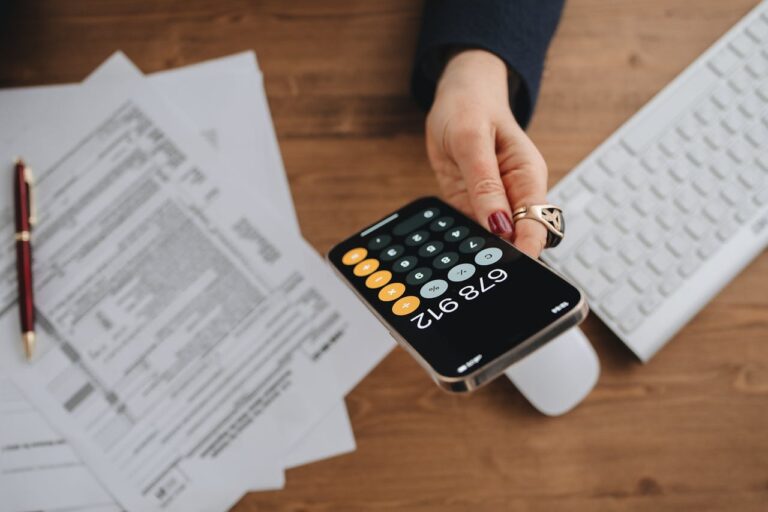 Persona haciendo la declaración de la renta usando una calculadora con los papeles de fondo