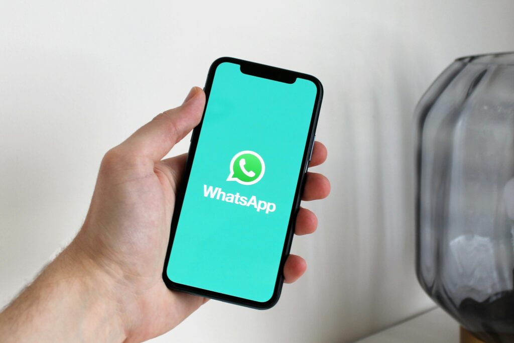 Mano sujetando un móvil con el simbolo de whatsapp